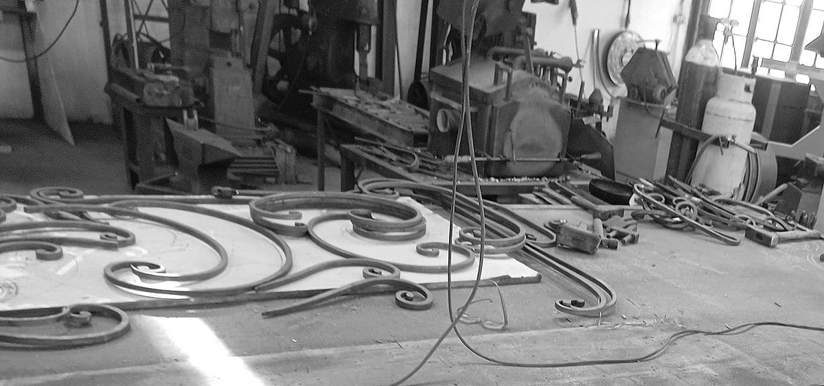 Werkplaats met gesmede krullen op de werktafel en smeedgereedschap op de achtergrond