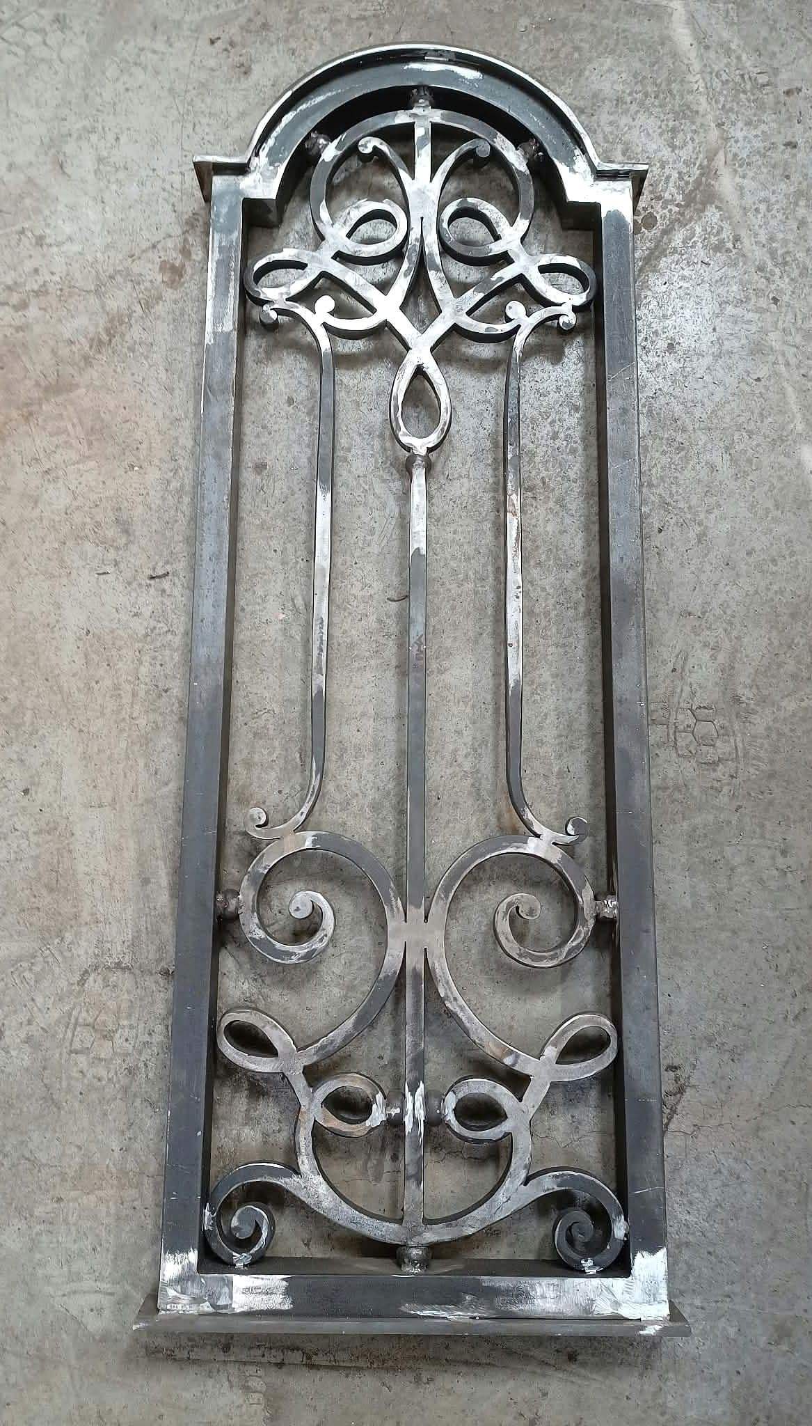 Handgesmeed boogvormig sierrooster in Art Nouveau-stijl met vervlochten lussen en krullen, blank staal